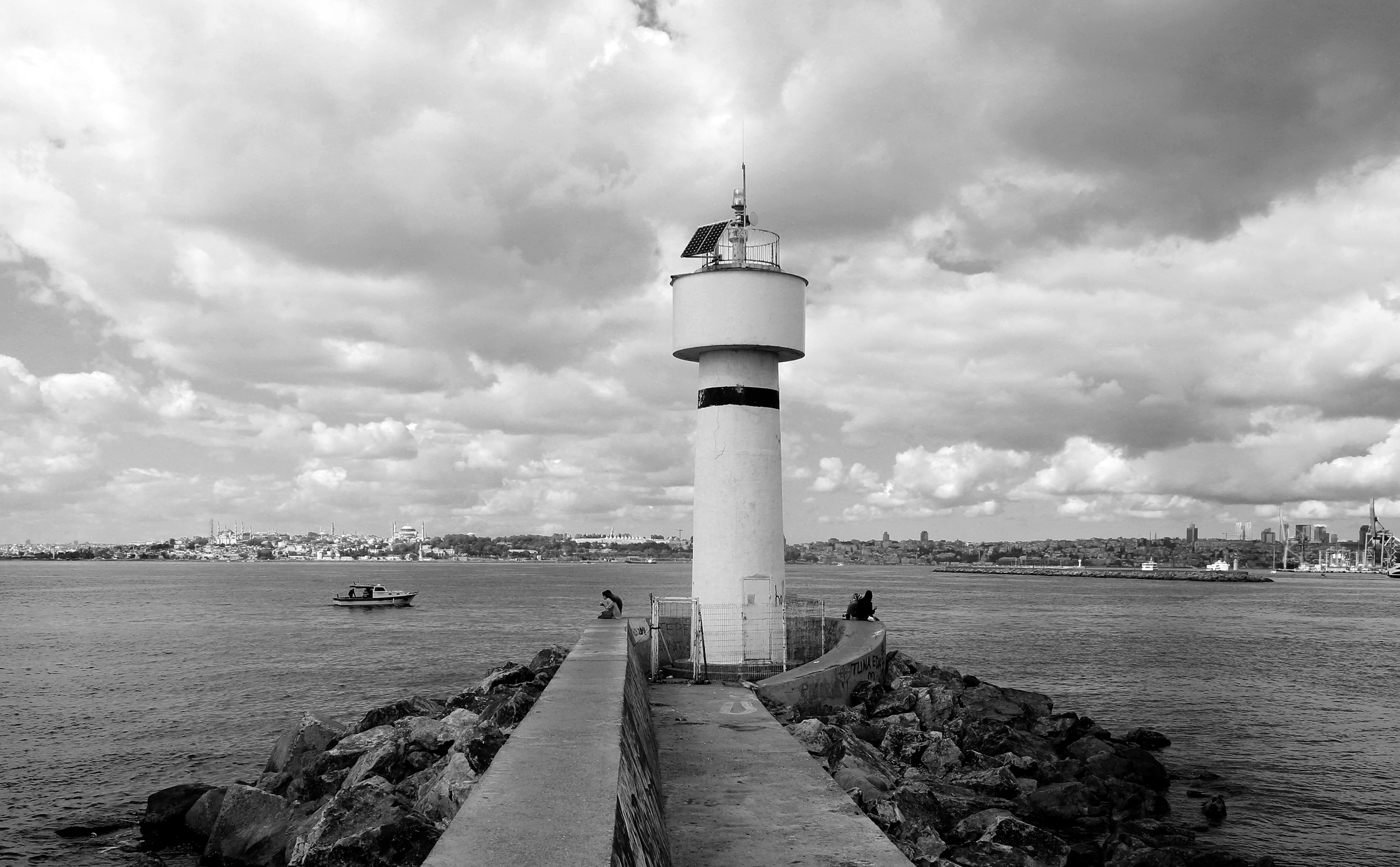 Photo d un phare noir et blanc surplombant une eau calme