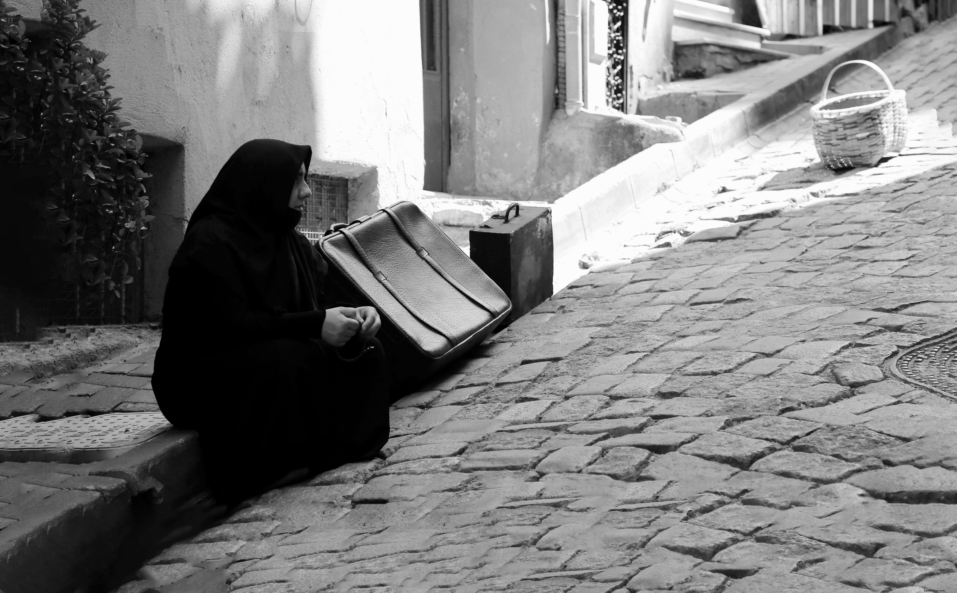 Voyageur assis sur le trottoir, entouré de valises