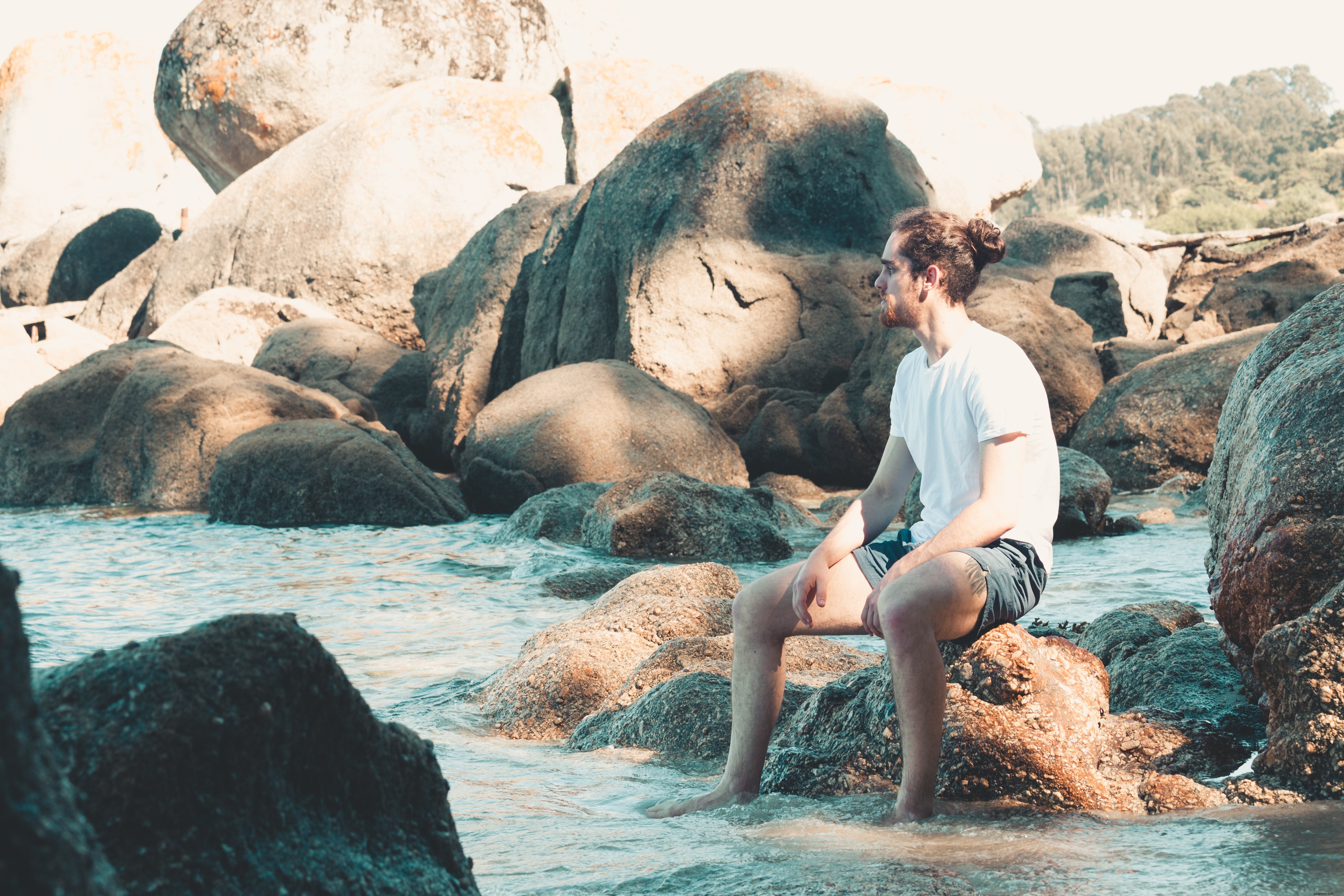 Homme assis sur un rocher, les pieds dans l eau – Photo