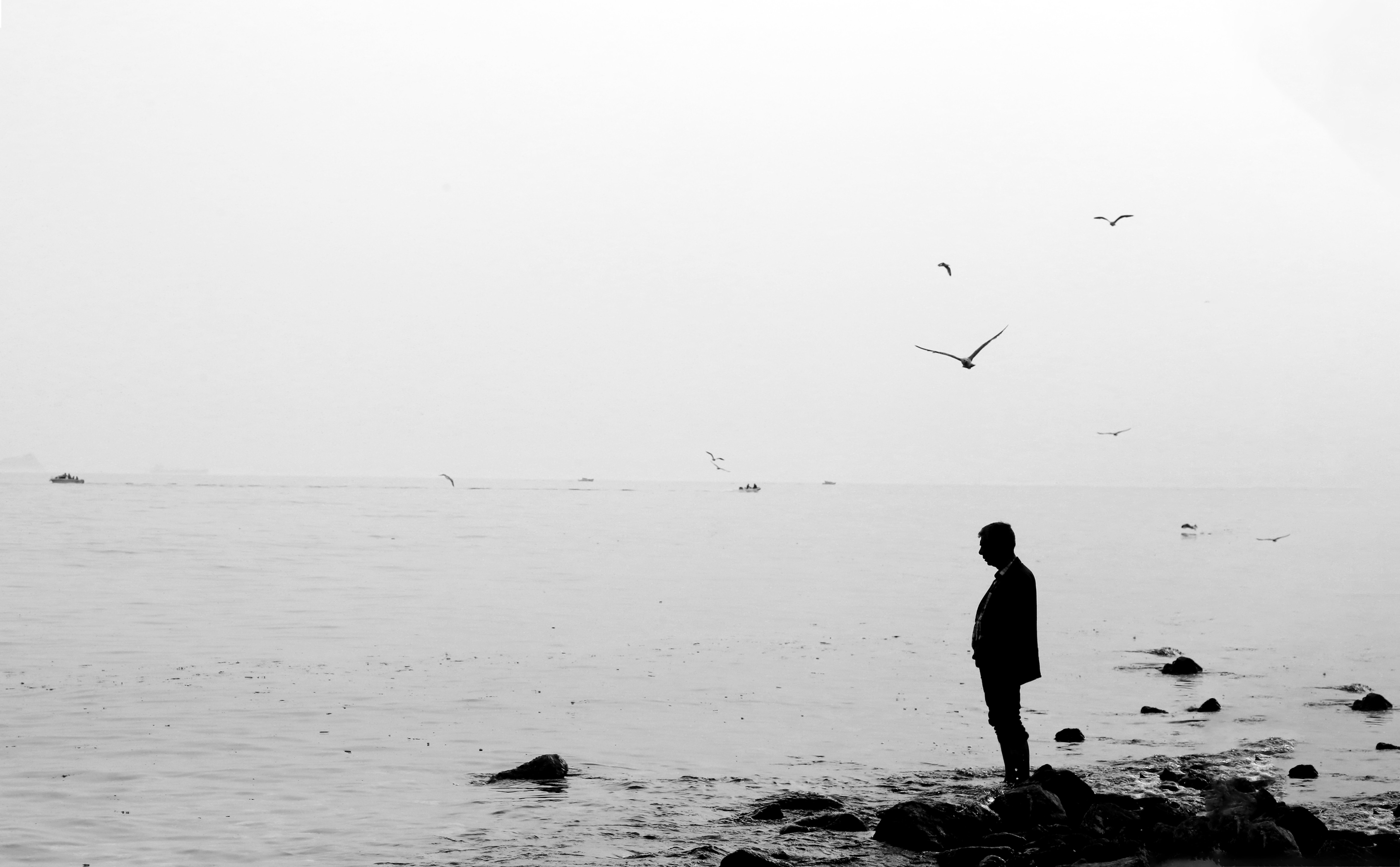 Silhouette debout sur des rochers au bord d une eau calme – noir et blanc