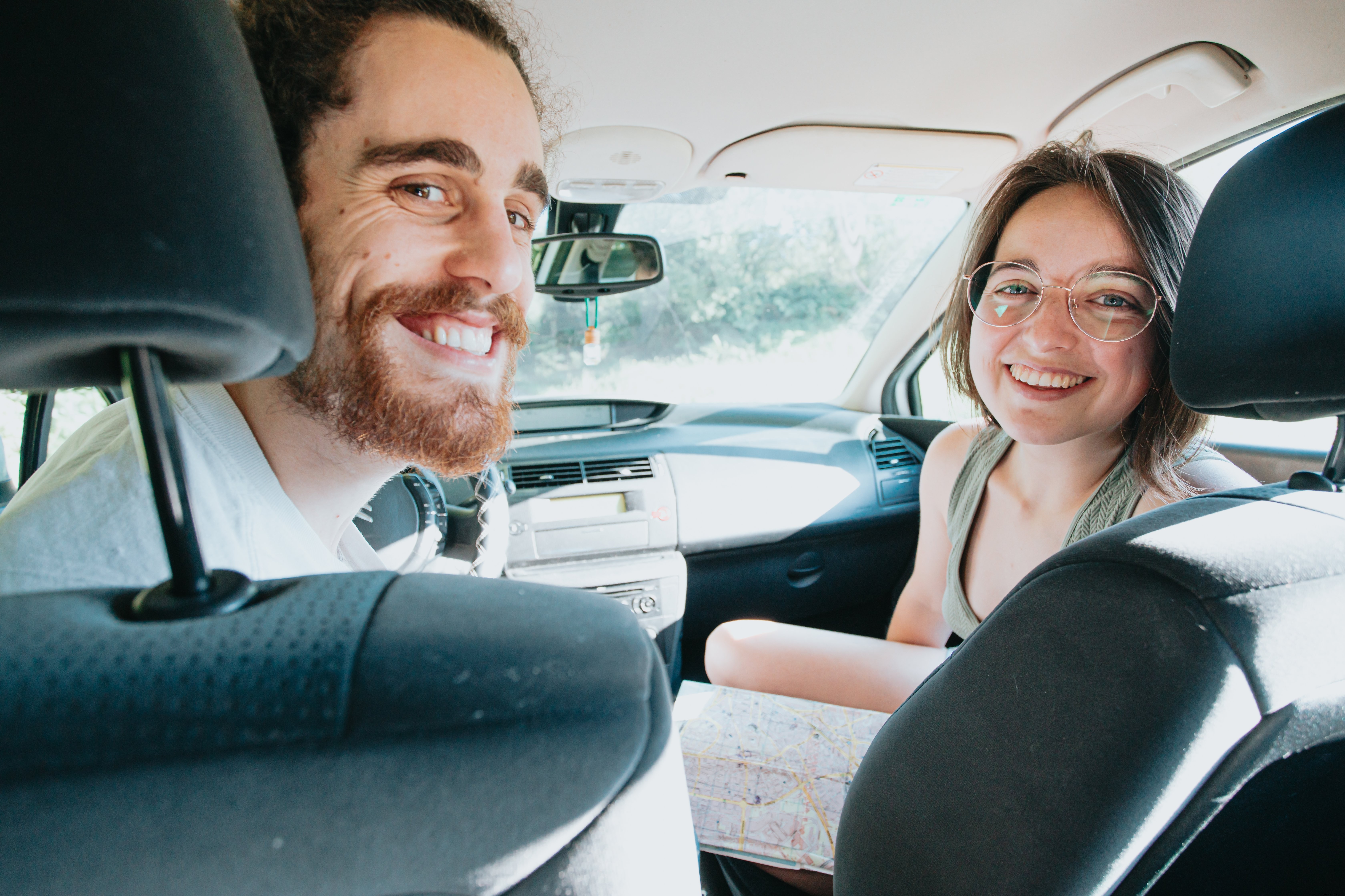 Deux voyageurs souriants dans une voiture, se retournant