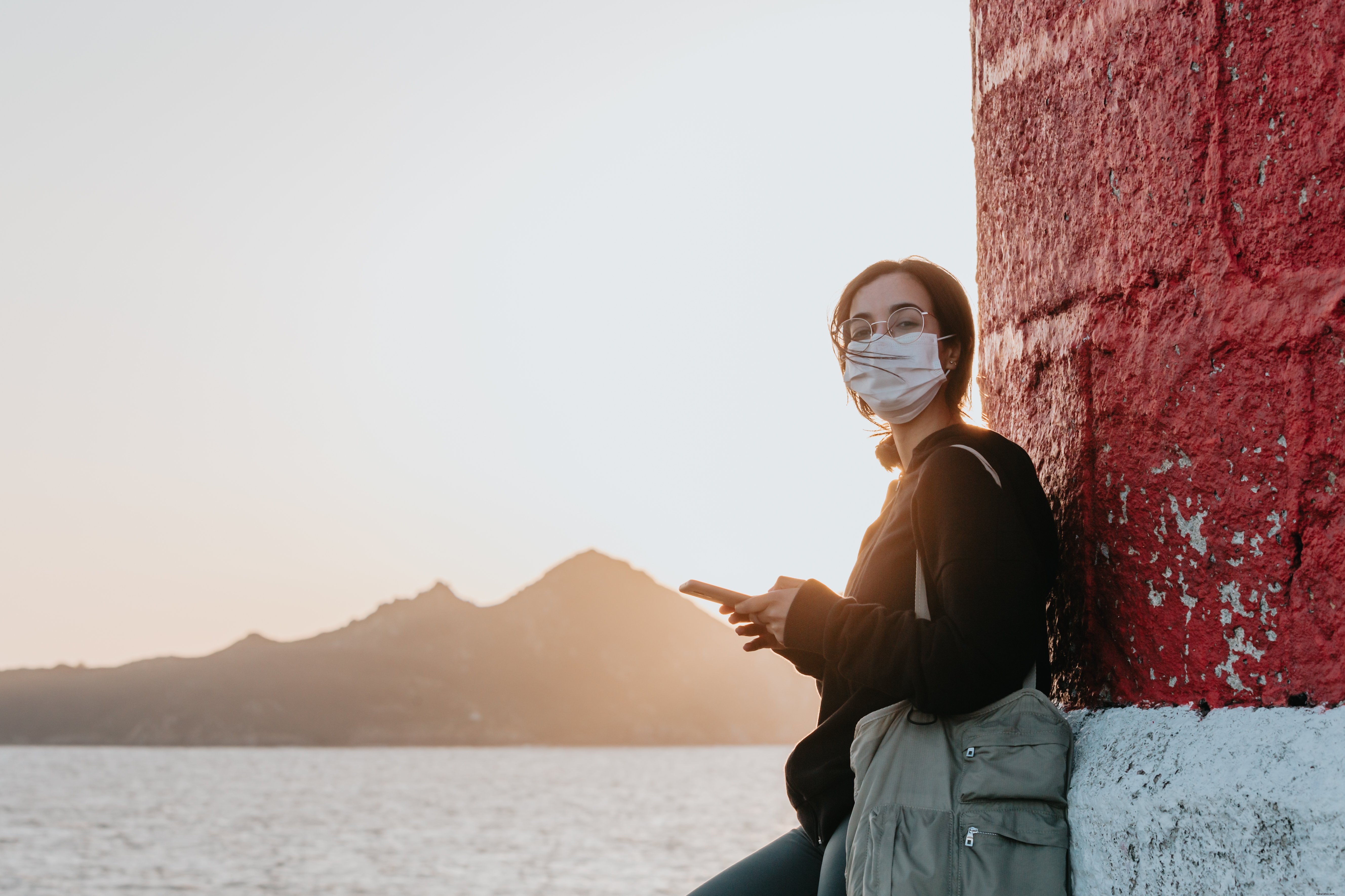 Femme masquée appuyée contre un mur au bord de l eau – Photo