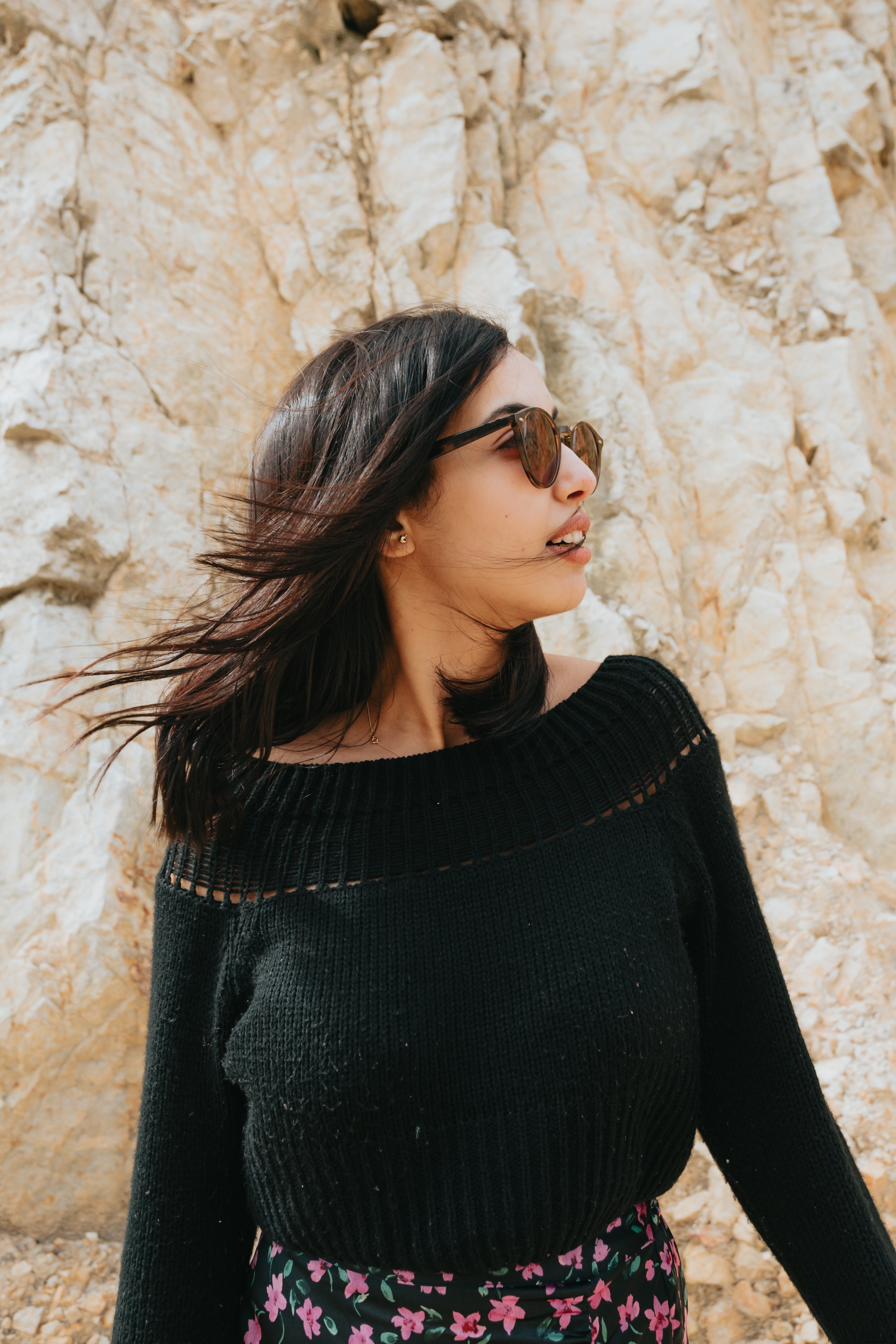Femme aux lunettes de soleil posant devant un paysage rocheux