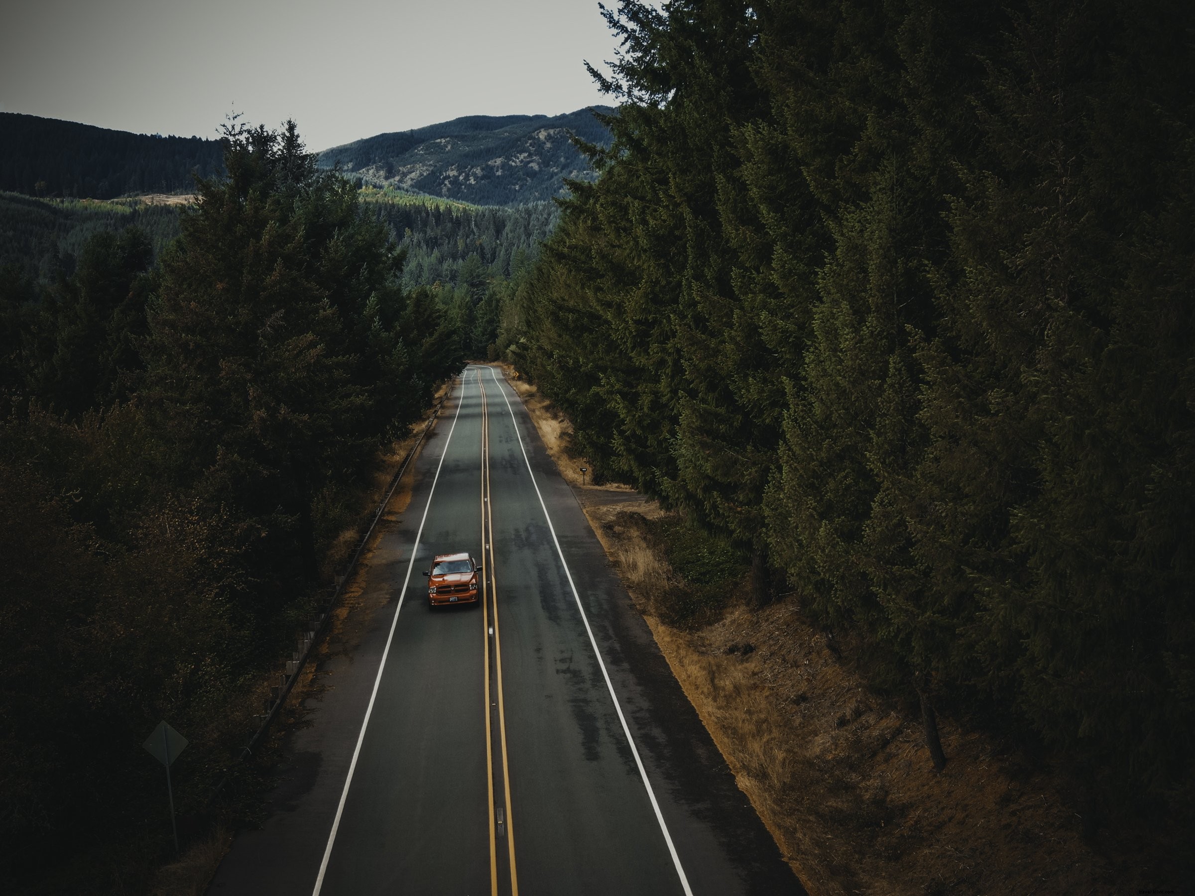 Voiture orange sur une route de campagne pavée