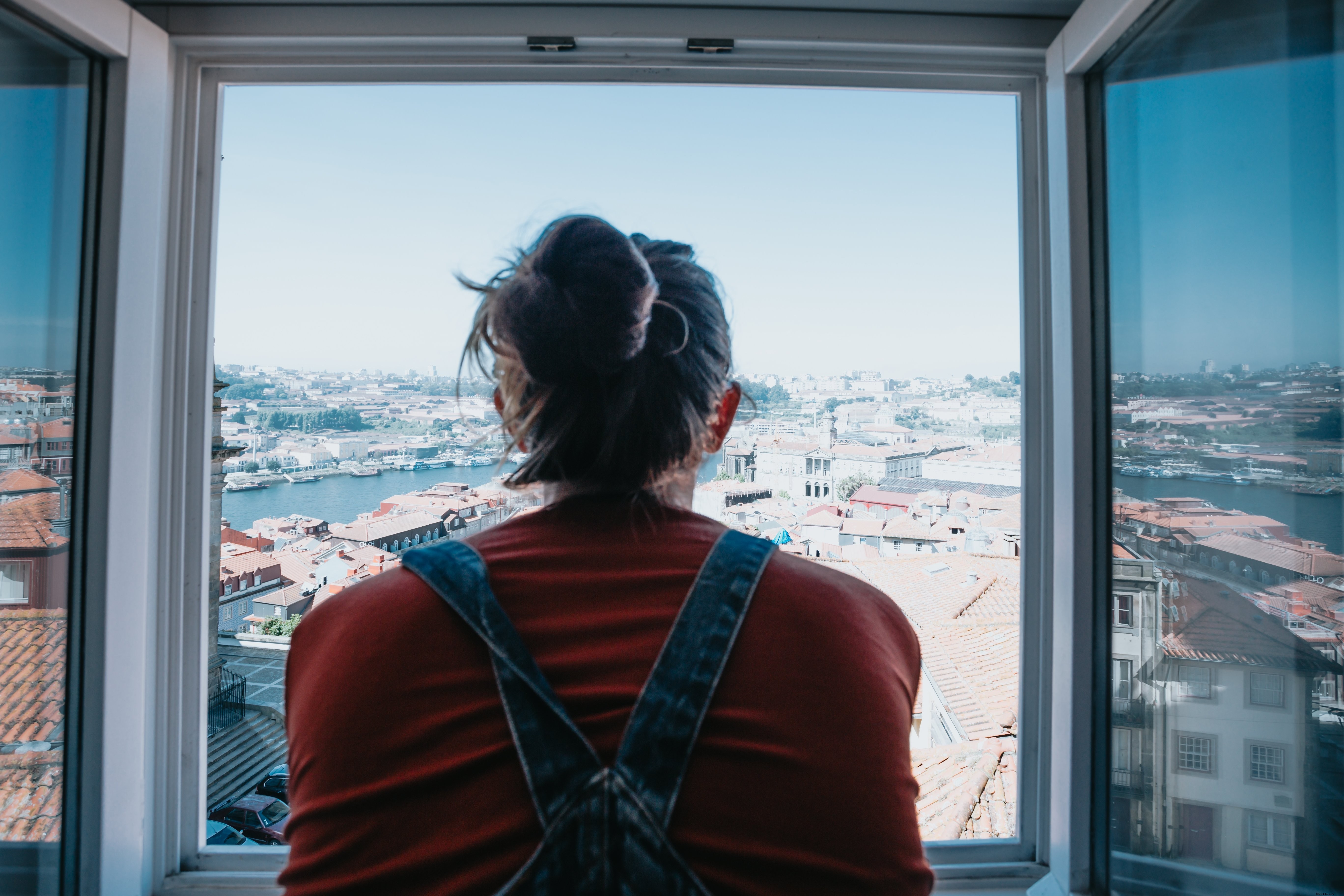 Une silhouette observe la ville depuis une fenêtre ouverte