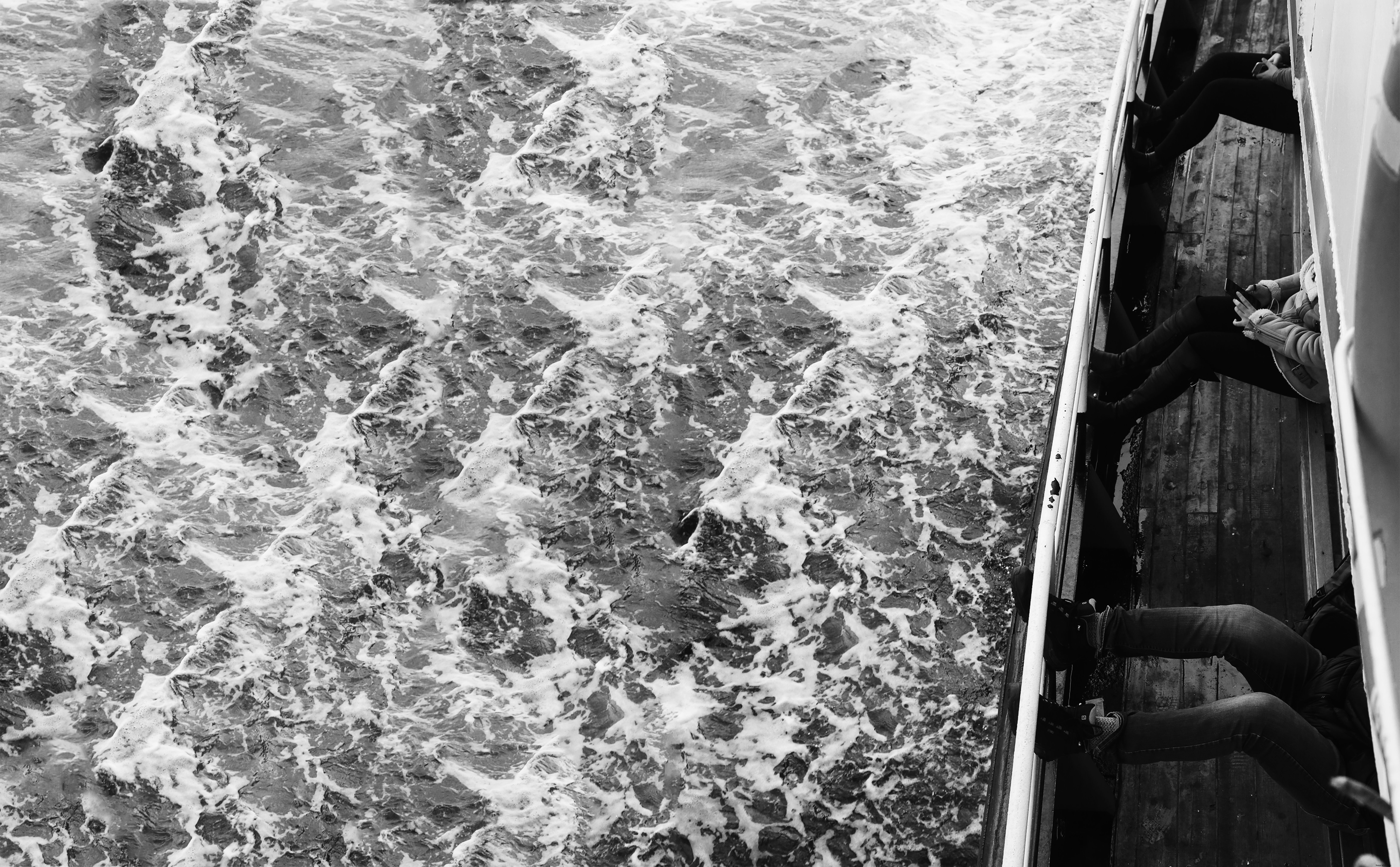 Photographie en noir et blanc de vagues et de passagers à bord d un bateau