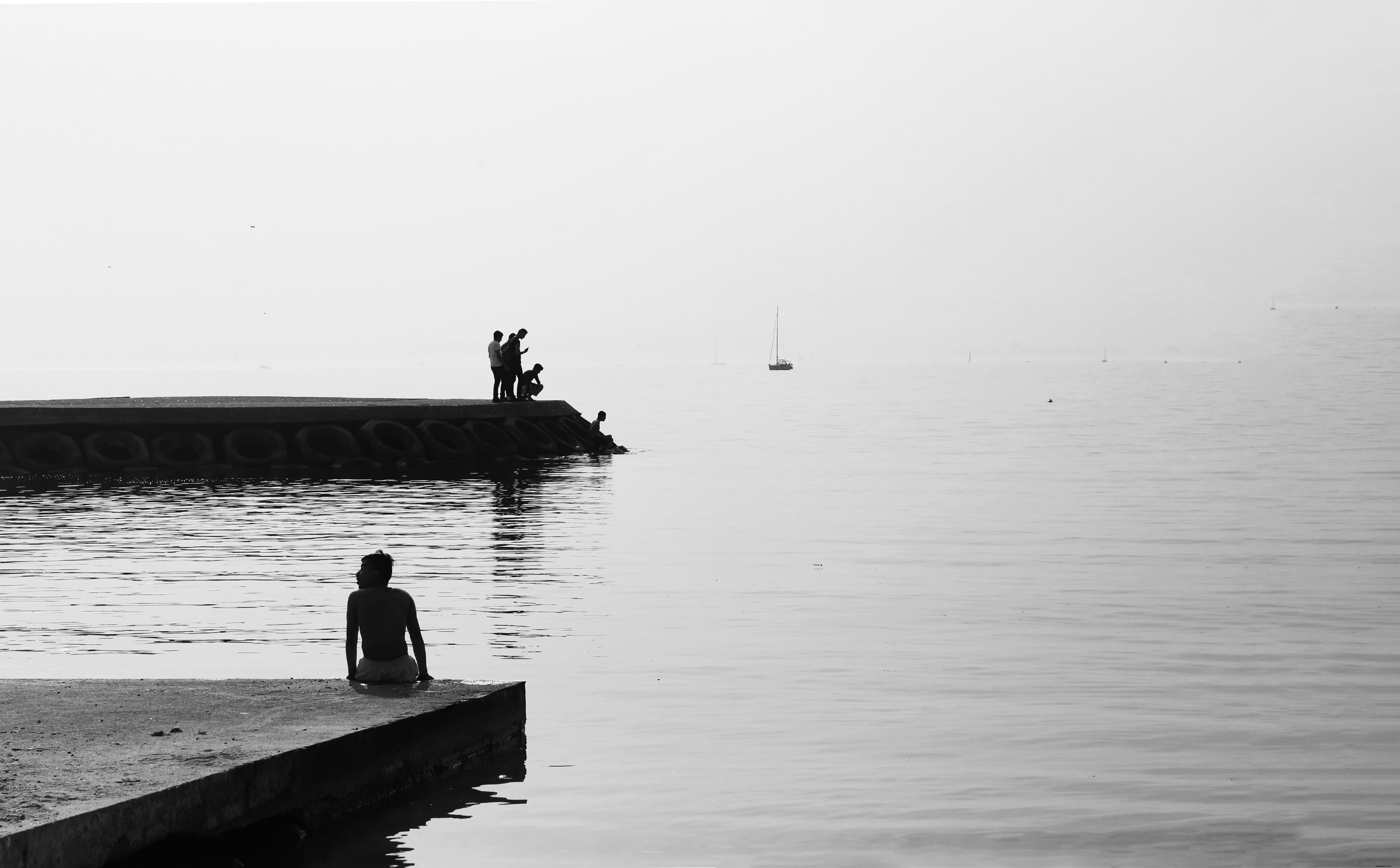 Photo noir et blanc de personnes sur une rive en béton, reflet d une eau calme