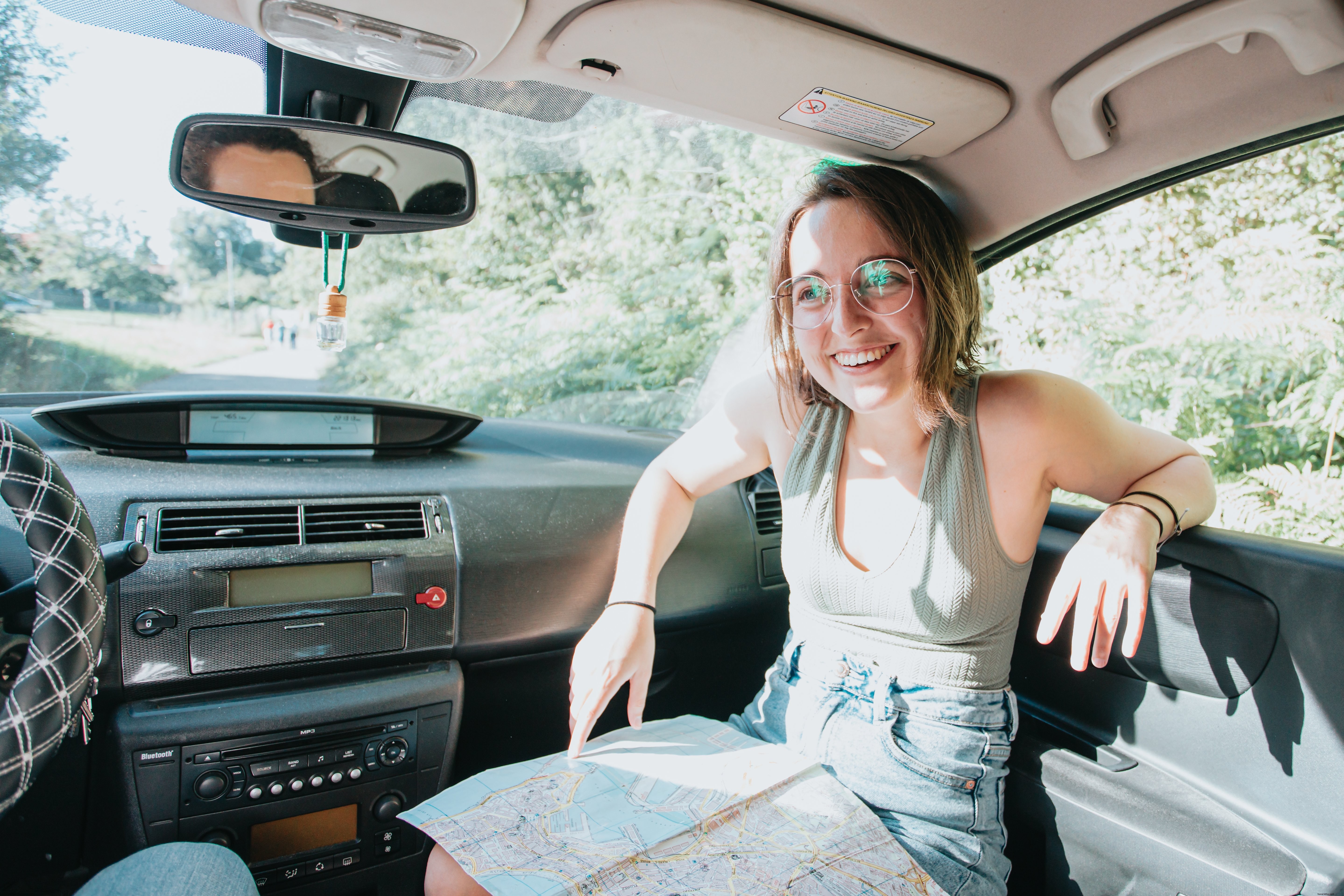 Femme souriante en voiture, carte déployée sur les genoux – Photo