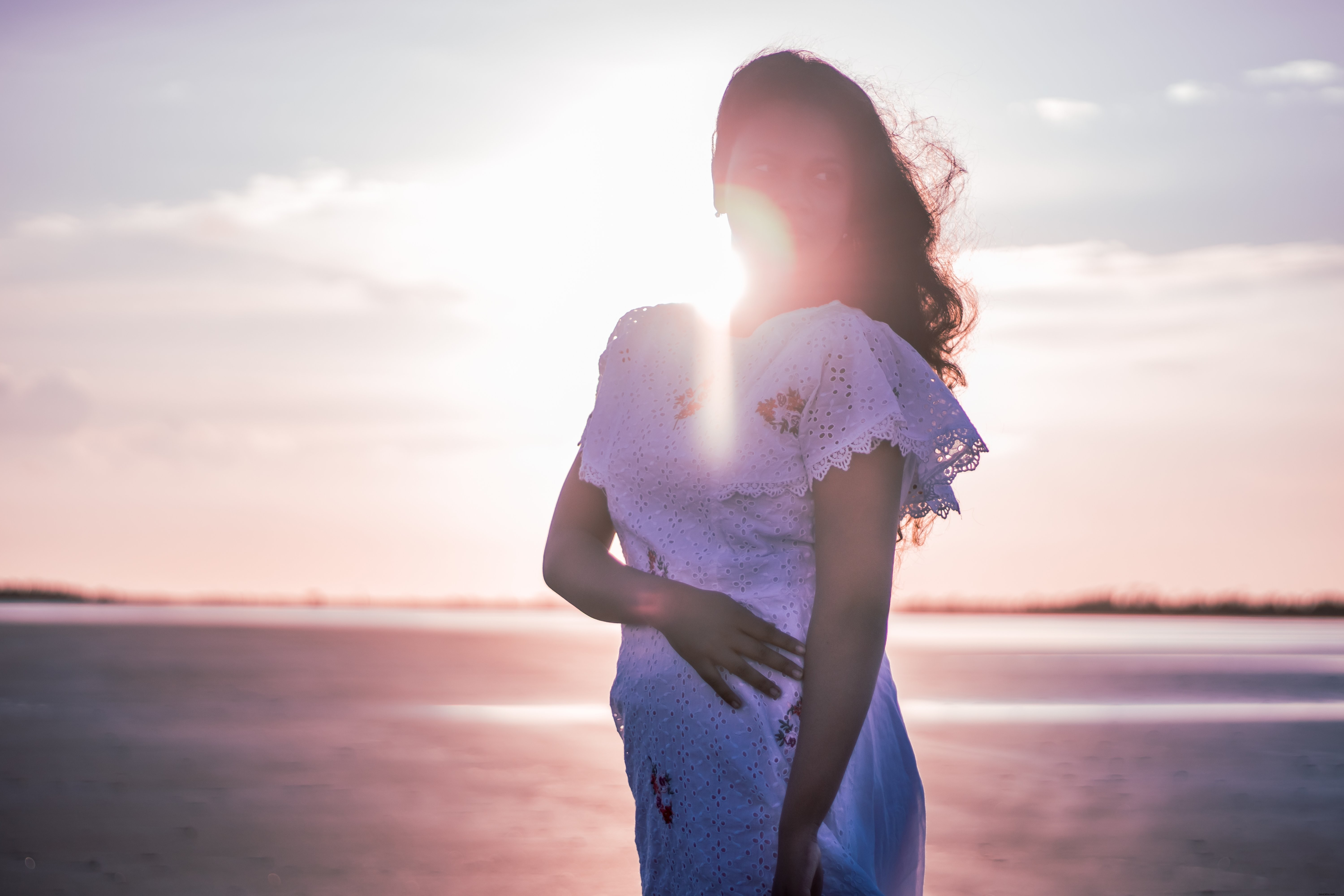 Silhouette en robe blanche au crépuscule sur la plage
